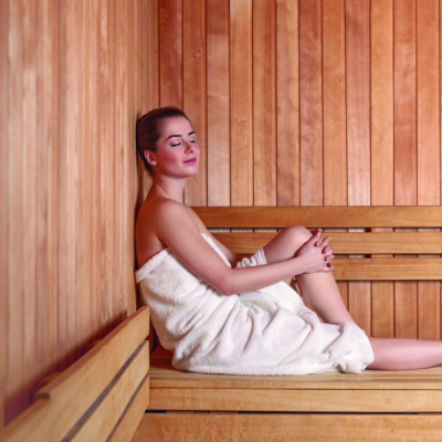 Frau mit Handtuch sitzt auf Saunabank